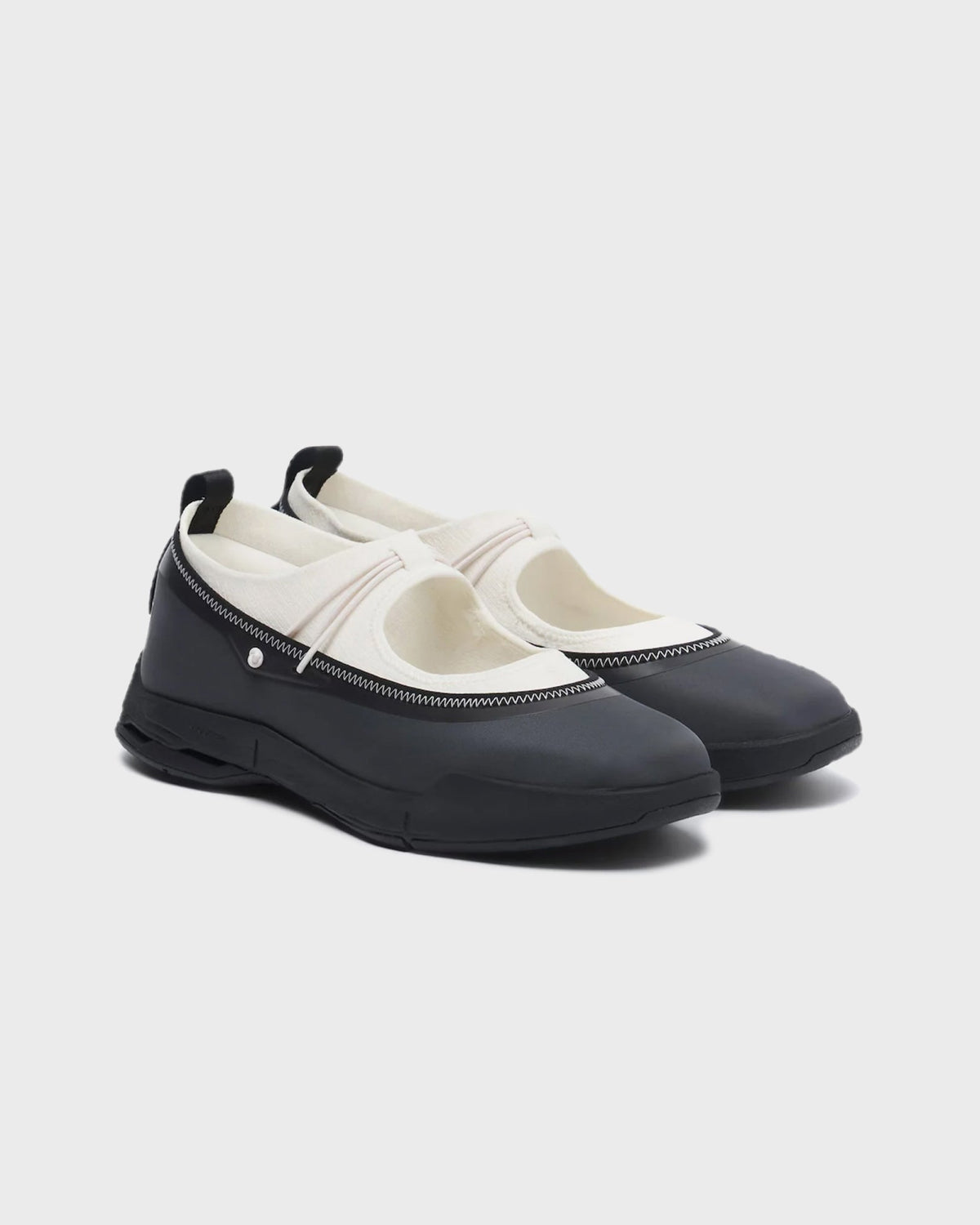 On Running women's mary jane sneakers in cream and black with elastic strap and rubber toe cap, angled pair view