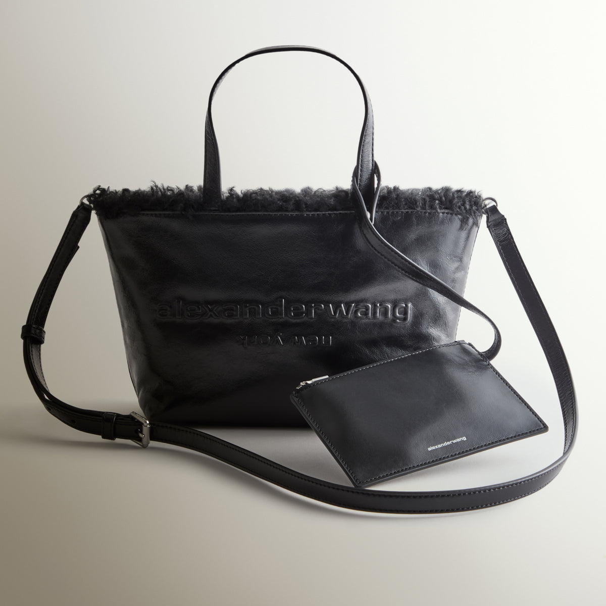 Alexander Wang black leather mini tote with shearling trim, embossed logo, crossbody strap and matching zip pouch