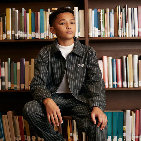 A child wearing a matching pinstripe suit from Kith Kids Fall 2023.