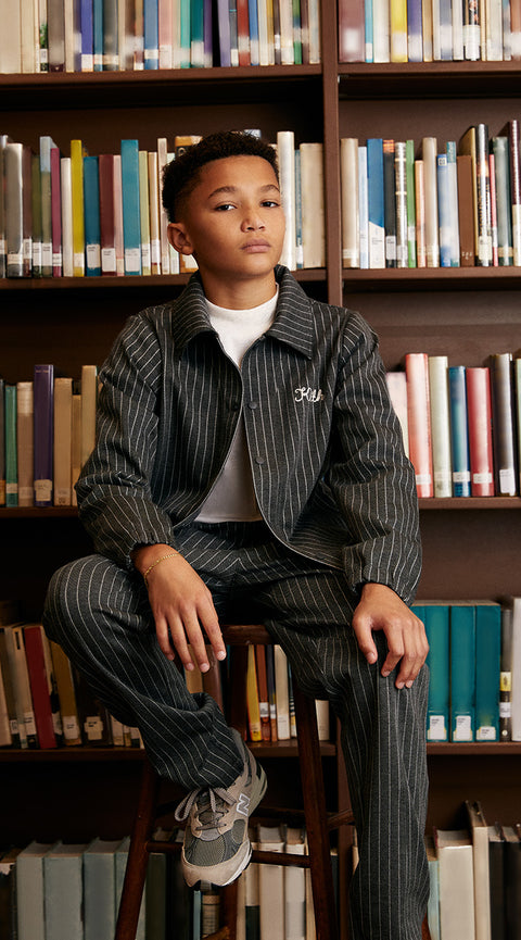 
        A child wearing a pinstripe Kith-branded jacket and matching pants from Kith Kids Fall 2023.
      
