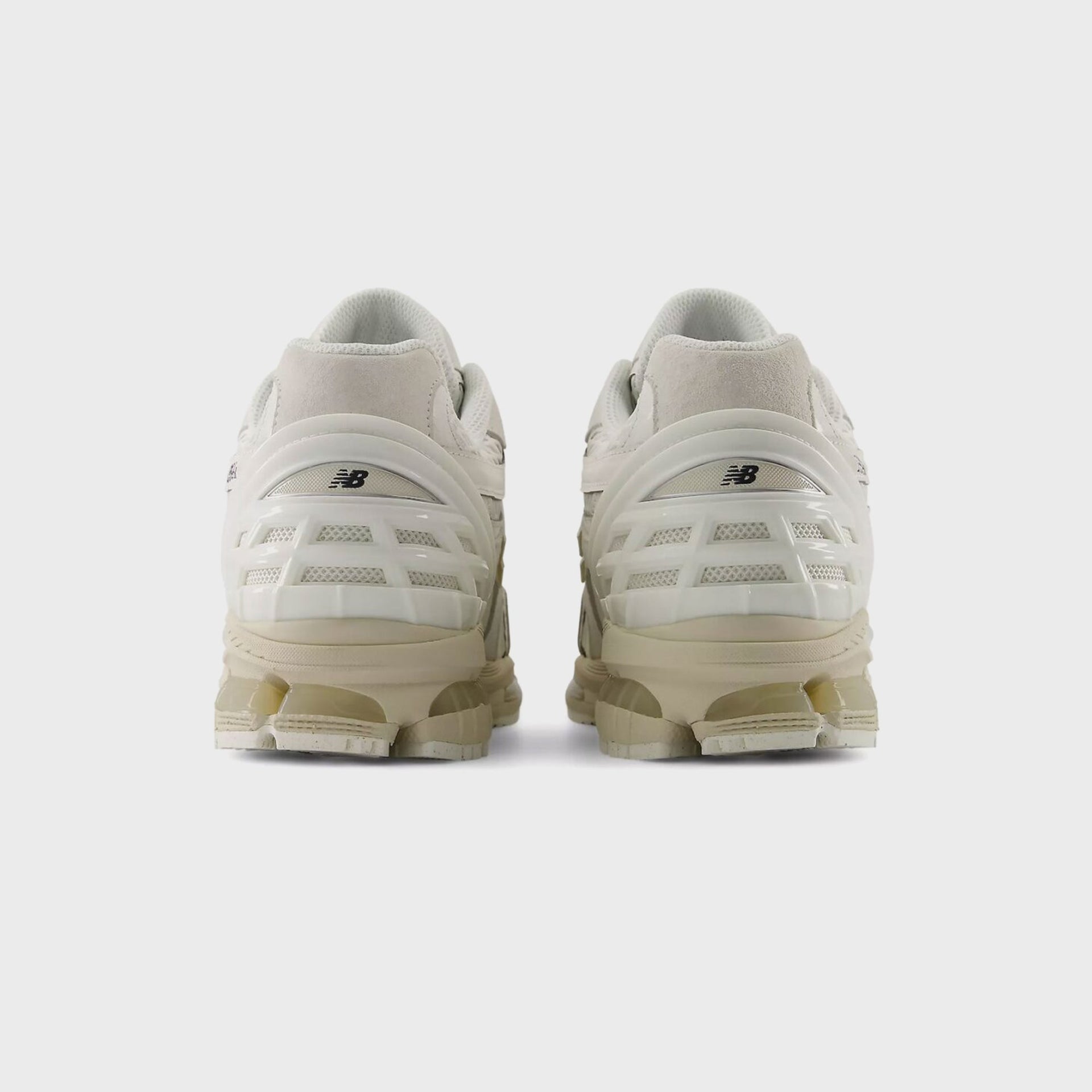 Rear heel view of a pair of New Balance 1954R Sea Salt sneakers showing the caged heel counter and tonal N logo