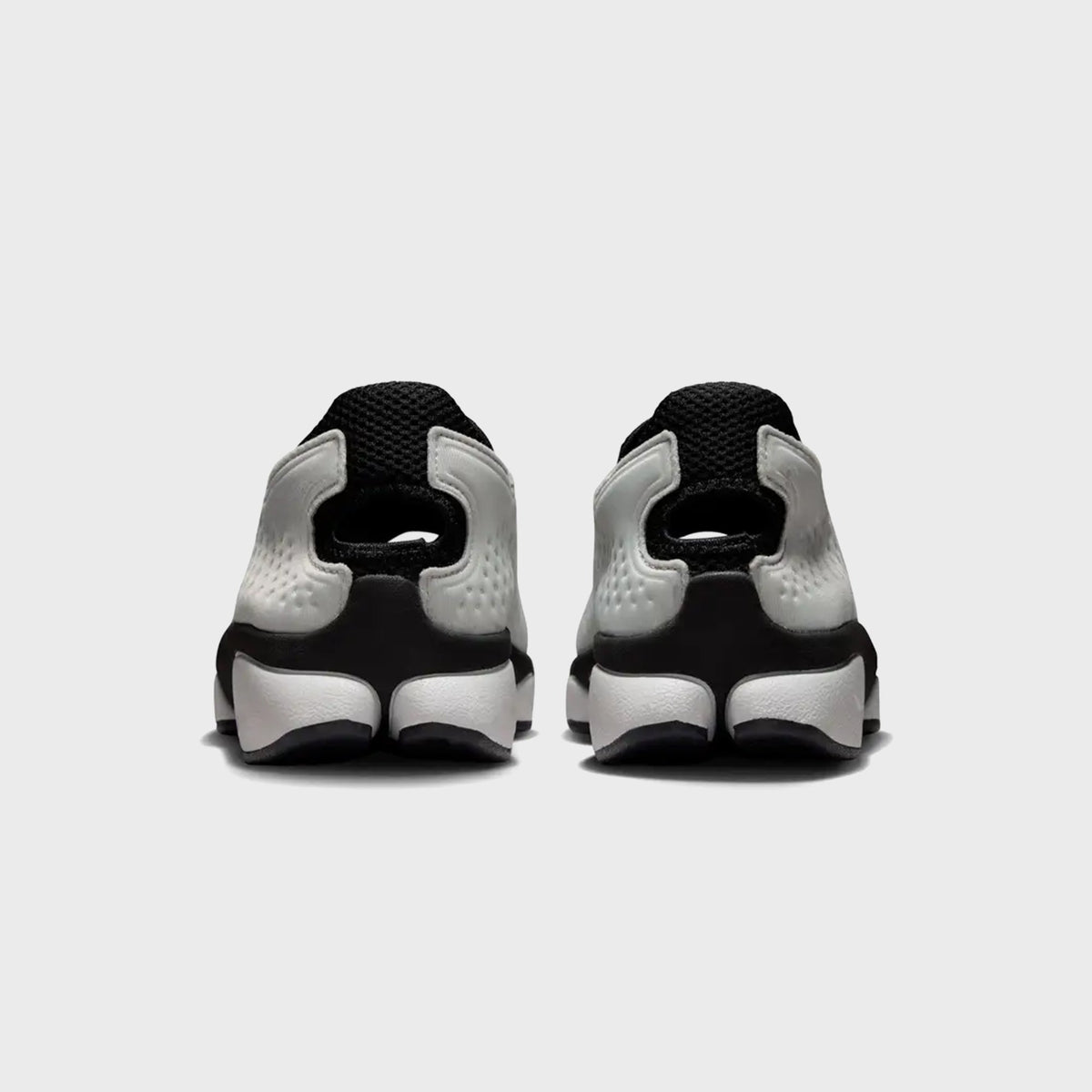 Nike Rift 2 split-toe sneakers in Black and Metallic Silver, rear view of the pair showing the cut-out heel loop
