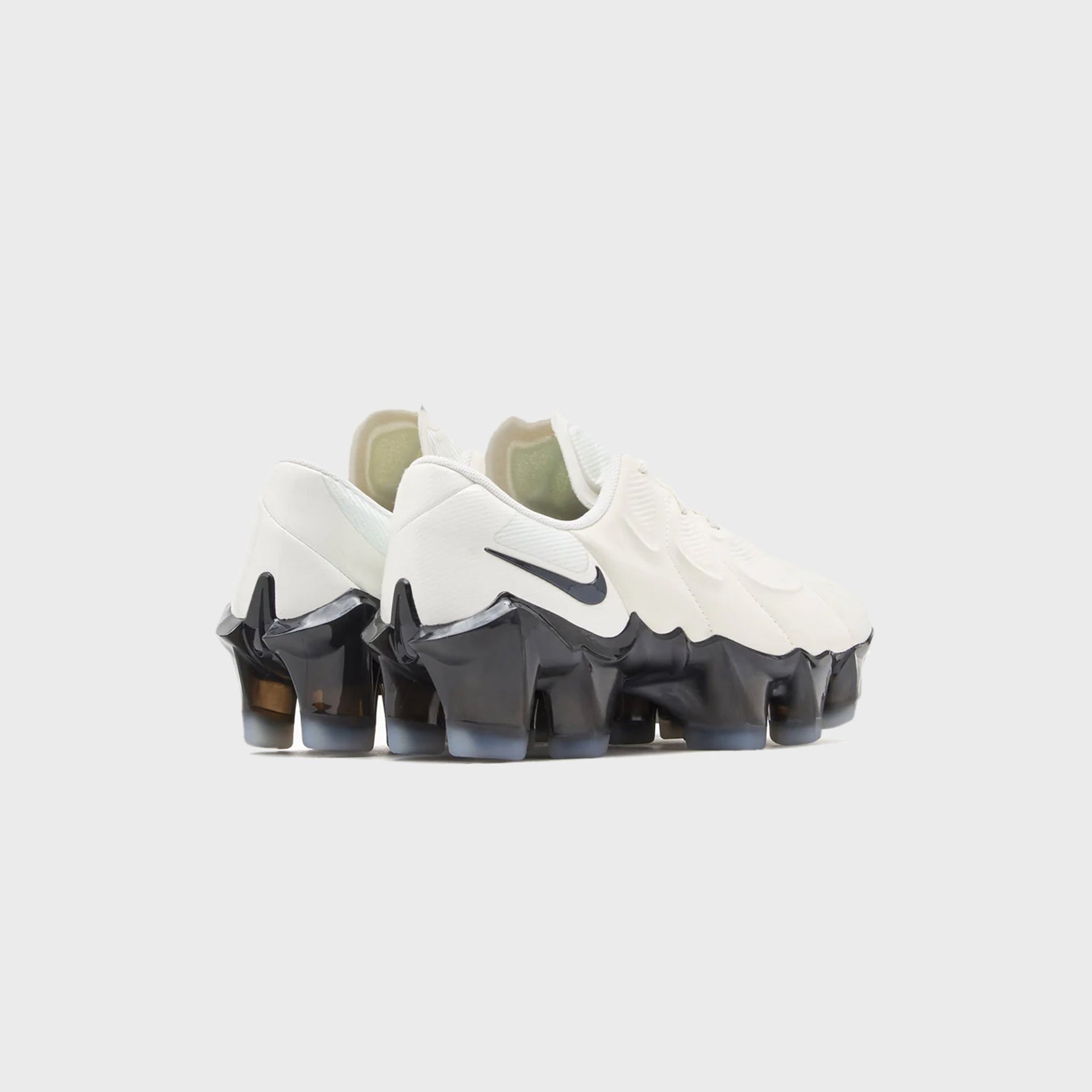 Pair of Nike WMNS First Sight Mirage sneakers in sail, rear three-quarter heel view with translucent black VaporMax soles