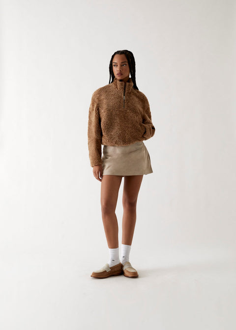 
            A model wearing a sherpa quarter-zip, suede skirt, and loafers from Kith Women Fall 2023.
          
